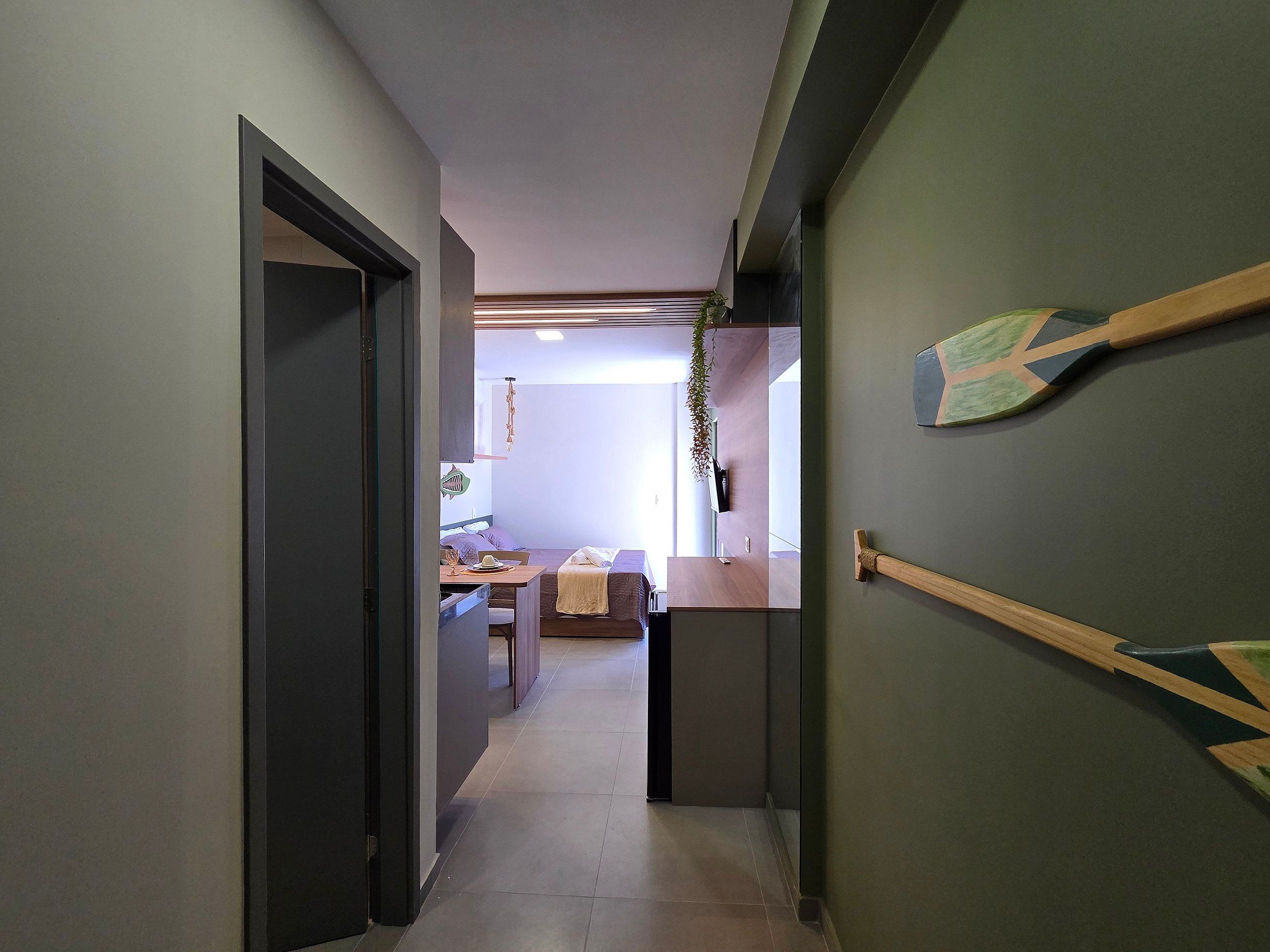 A hallway leading to a dining area with a table and chairs, a hanging plant, and a wooden door frame.