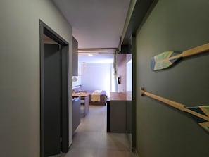Un corridoio che conduce a una zona pranzo con tavolo e sedie, una pianta pensile e un portale in legno.