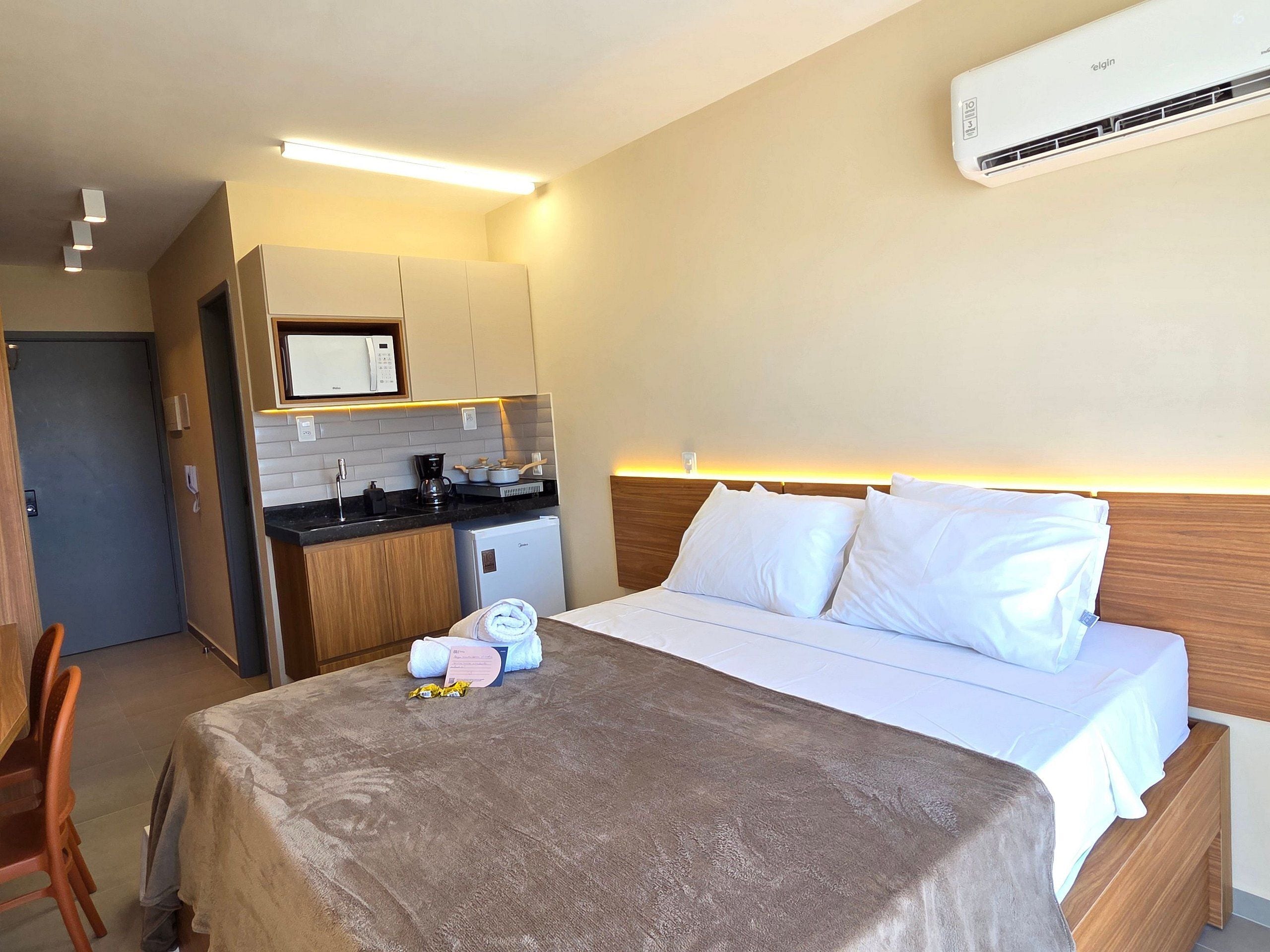 Een hotelkamer met een bed, een kitchenette, een magnetron en een airconditioning.