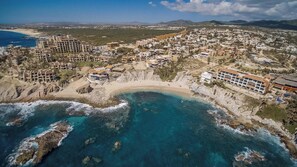 Vue aérienne d’une ville côtière avec une plage, des bâtiments et une côte rocheuse.