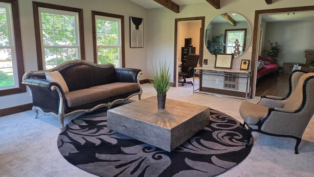 A spacious living room with a large window, a fireplace, and a round mirror. - Spacious 4BR Rockville Yard, BBQ & Free Parking (Rockville)