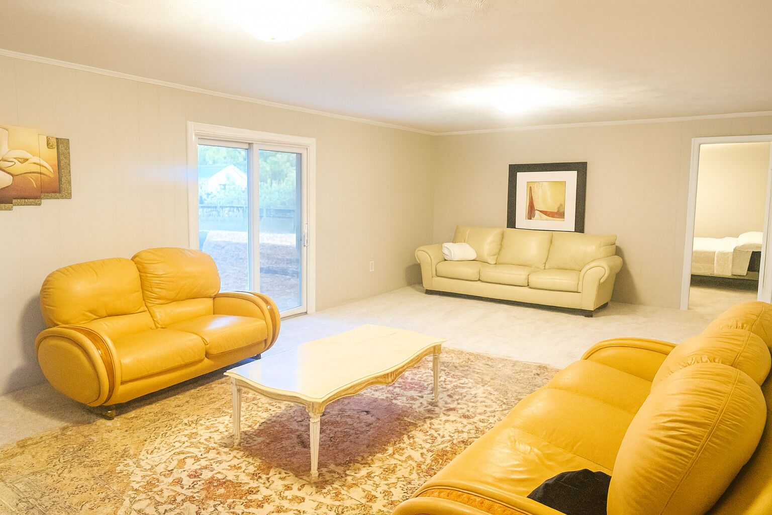 A living room with a yellow sofa, a beige sofa, and a coffee table.