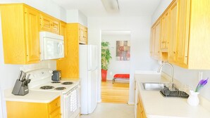 A compact kitchen with wooden cabinets, a microwave, stove, and sink. - Spacious 4BR Rockville Yard, BBQ & Free Parking (Rockville)