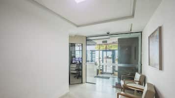 Um corredor com porta de vidro que dá para uma área de estar com cadeiras e uma televisão.