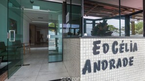 A reception area with a tiled wall displaying 'ED CÉLIA ANDORADE' and a glass entrance.