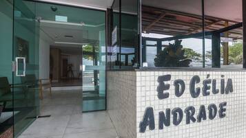Uma área de recepção com uma parede de azulejos exibindo 'ED CÉLIA ANDORADE' e uma entrada de vidro.