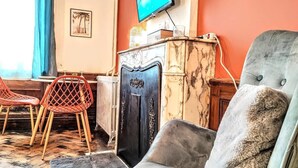 Un salon avec un canapé, des fauteuils, un téléviseur et une cheminée.