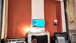 Une pièce avec une cheminée, un téléviseur fixé au-dessus et deux fauteuils.