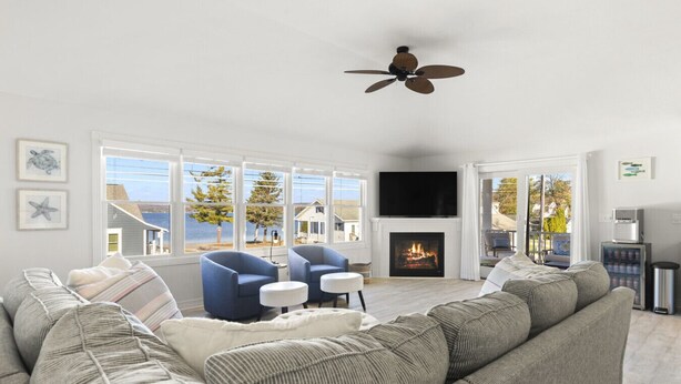 A living room with a large sofa, two armchairs, a fireplace, a television, and a ceiling fan. - Modern-coastal retreat with lake views, covered deck, and walkable downtown Beulah location. (Beulah)