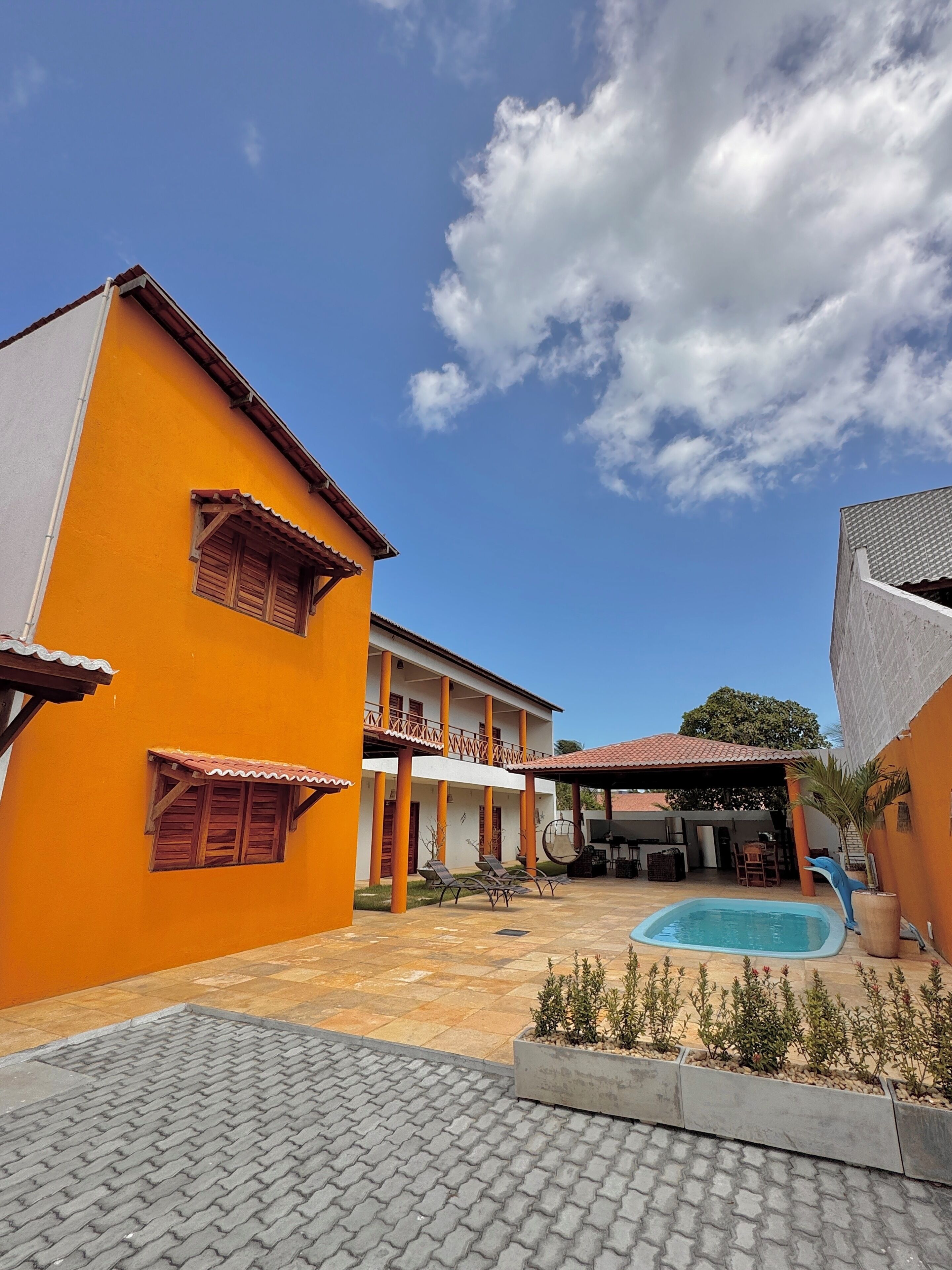 Un patio con piscina, mobiliario exterior y zona cubierta.