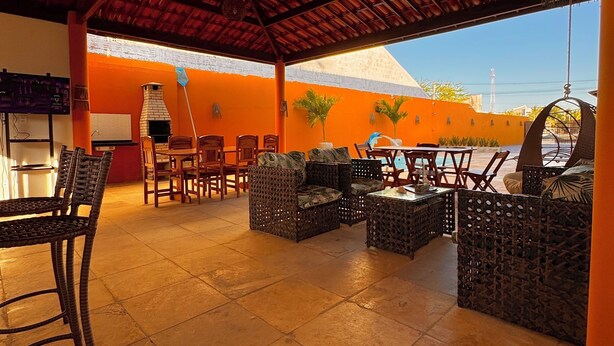 An outdoor patio area with wicker furniture, a brick oven, and a view of a building with a pyramid-like structure. - Pousada Du Vento (Cruz)