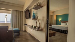 Une chambre d’hôtel avec un lit, un canapé, une télévision, une petite table et une fenêtre avec des rideaux.