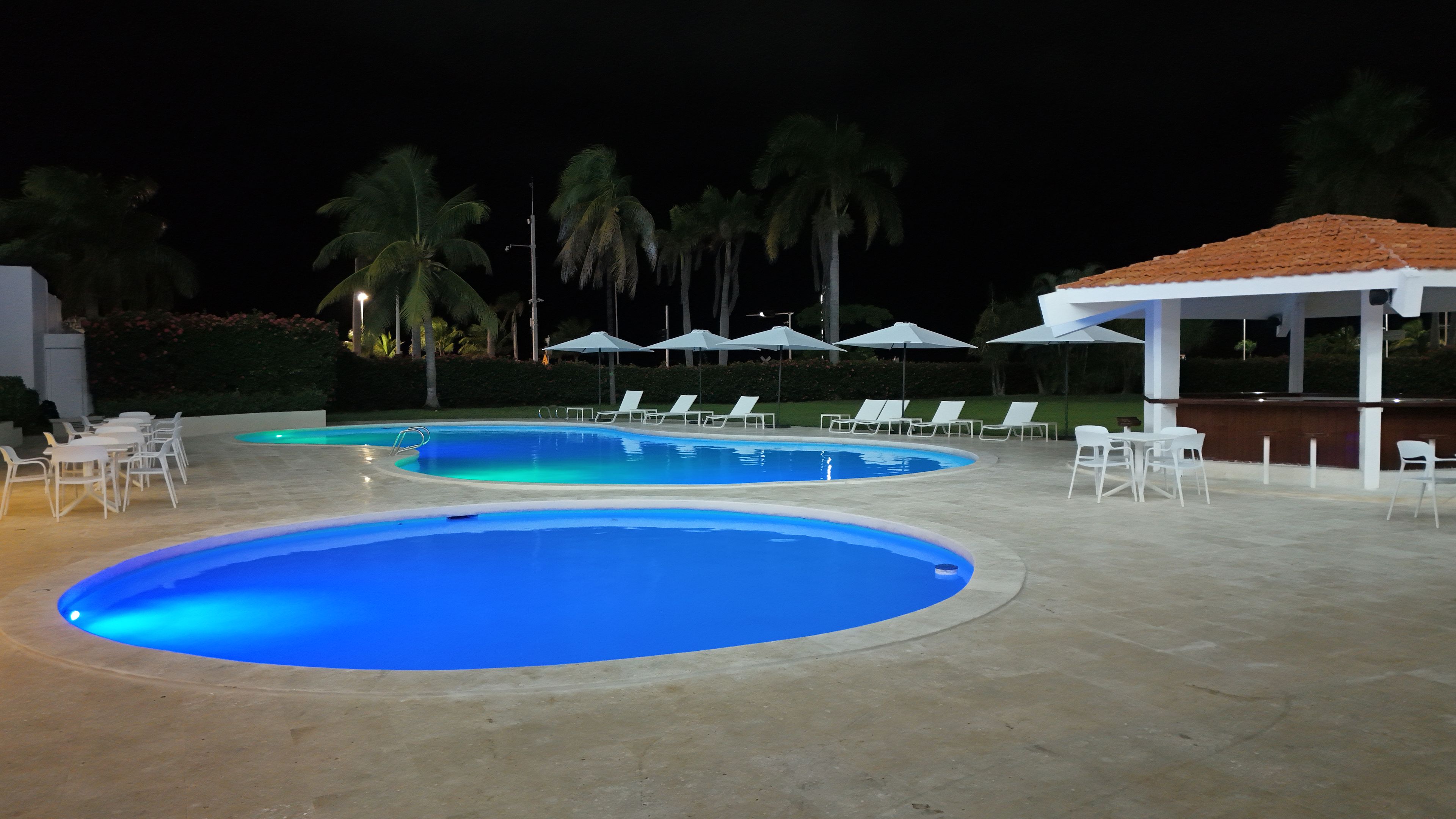 A swimming pool area with lounge chairs and umbrellas.