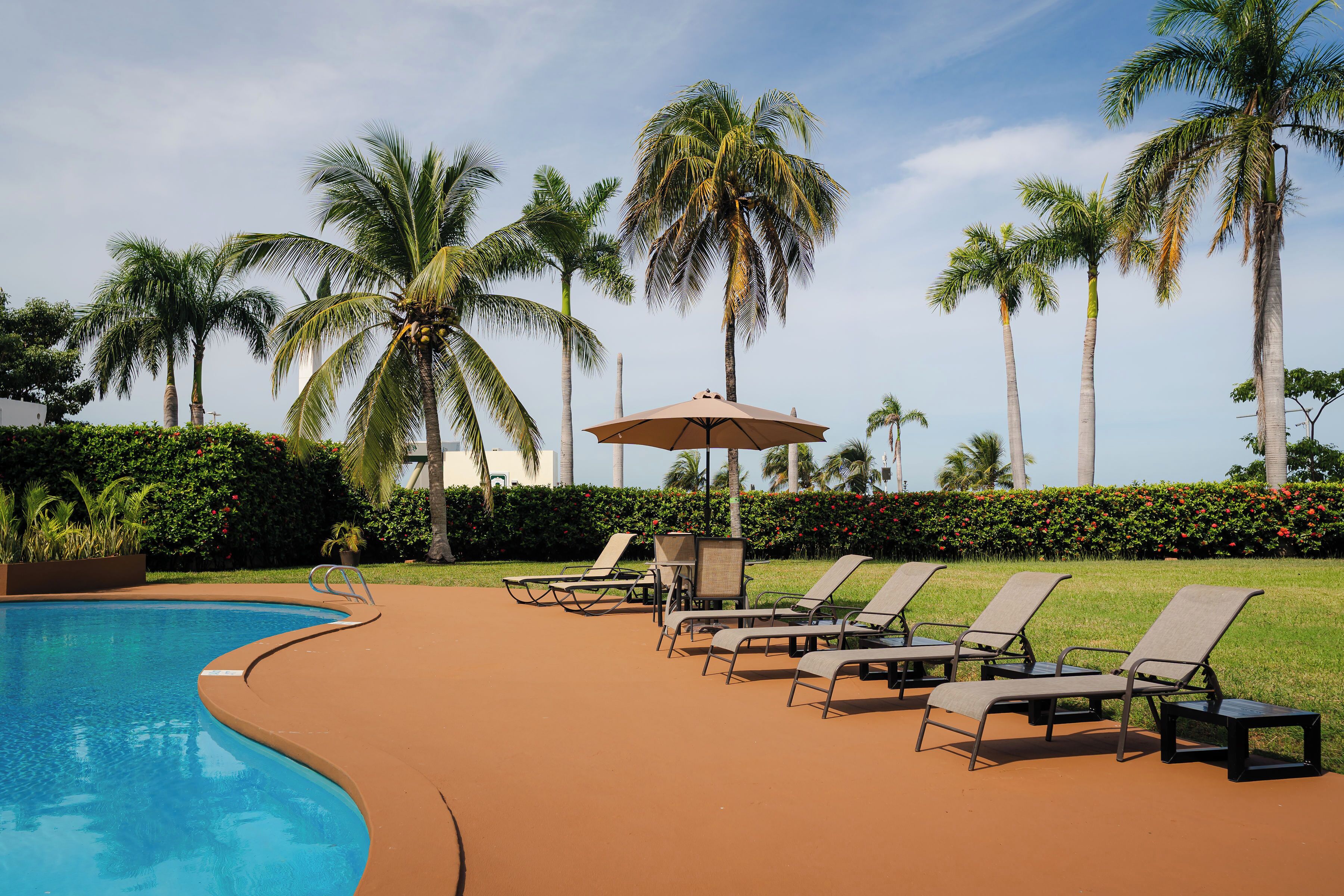 Een buitenzwembad, ligstoelen bij het zwembad