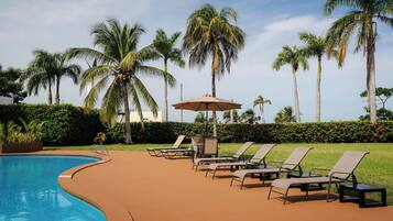 Een buitenzwembad, ligstoelen bij het zwembad