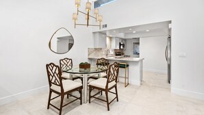 A modern kitchen with white cabinets, a marble countertop, and a stainless steel refrigerator. - NEW! Mariposa Hideaway by GPM -Chic Ironwood CC Condo (Palm Desert)