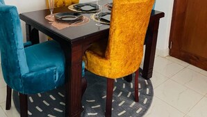 Comedor con una mesa dispuesta para cuatro personas, con dos sillas azules y dos amarillas.