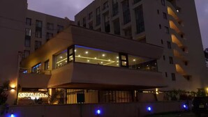 Ett hotell med flera våningar, ett iögonfallande skylt med texten ”CORAL BELLS”, stora fönster och en modern arkitektonisk design.