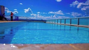 En klarblå pool med en glasvägg och ett metallstaket.
