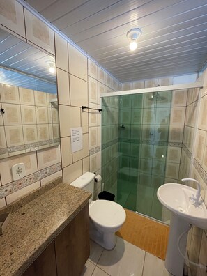 A bathroom with a glass-enclosed shower, a toilet, and two sinks. - Estação Do Mar  (Florianópolis)