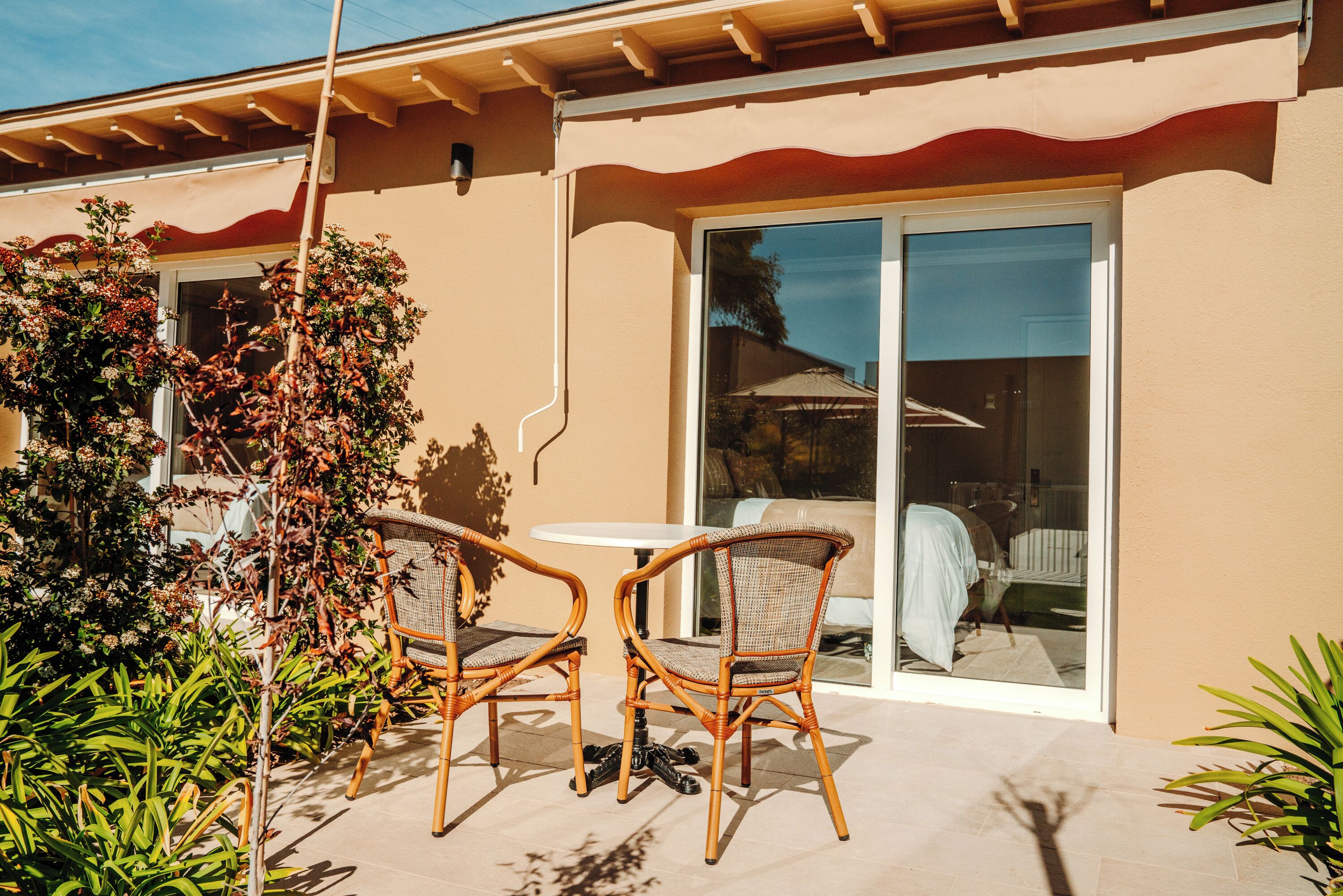 An outdoor patio with wicker chairs and a table, a sliding glass door, and a covered outdoor seating area.