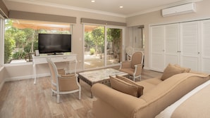 A spacious living room with a large TV, comfortable seating, and a sliding glass door leading to a garden. - Hacienda Huamalata (Ovalle)