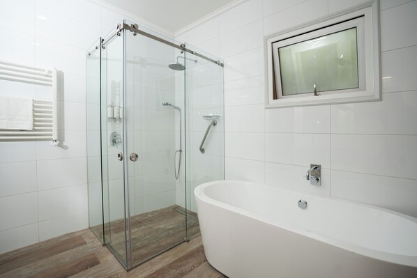 A modern bathroom with a glass-enclosed shower, a freestanding bathtub, and a wall-mounted sink. - Hacienda Huamalata (Ovalle)