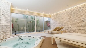 A modern spa area with a hot tub, lounge chairs, and a glass wall with plants. - Hacienda Huamalata (Ovalle)