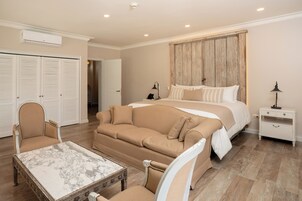 Un dormitorio con una cama grande, un sofá, una silla, una mesita de noche y una mesa de centro de mármol.
