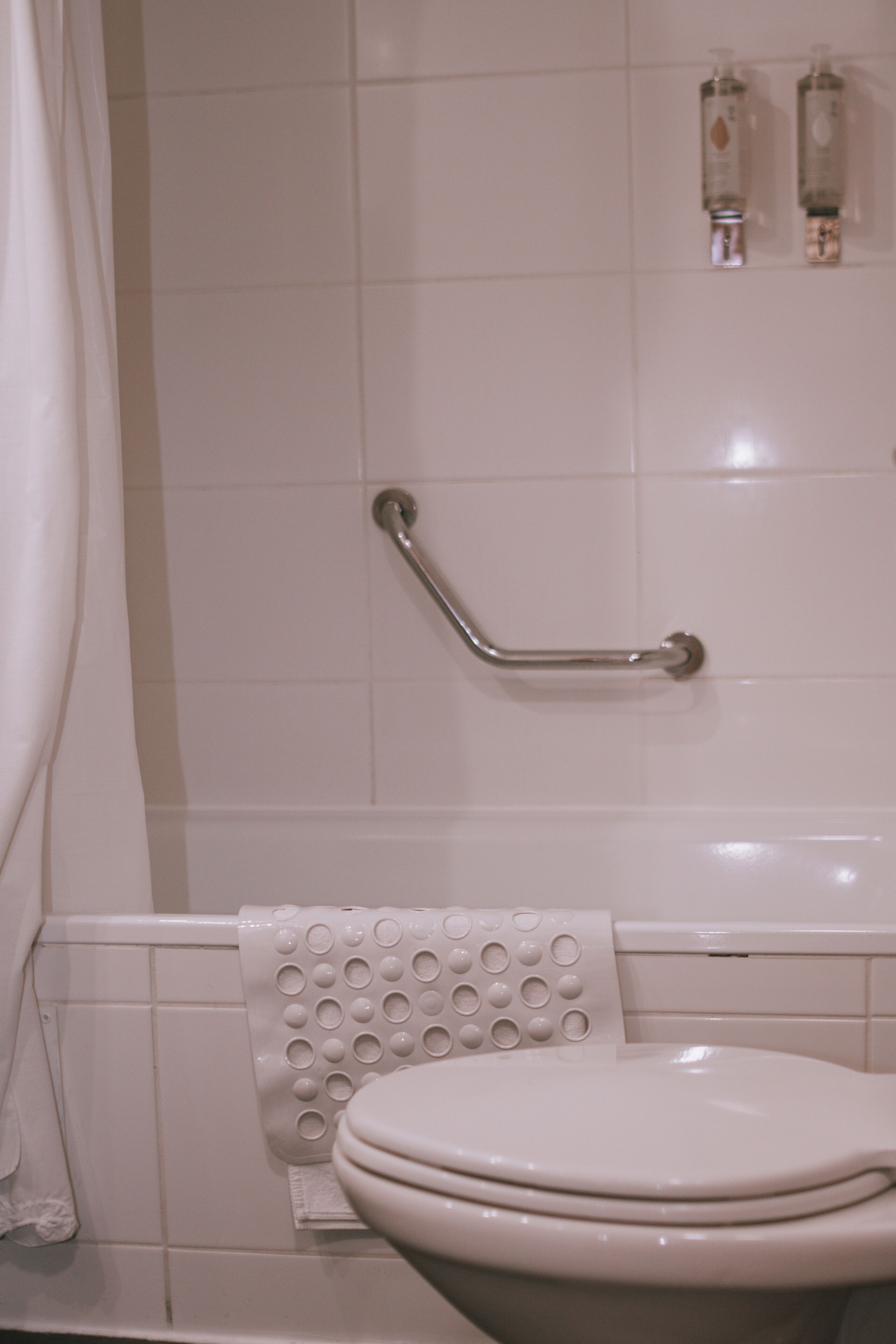 A bathroom with a white toilet, a grab bar, and a towel rack with a white towel.