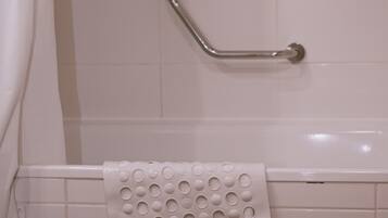 A bathroom with a white toilet, a grab bar, and a towel rack with a white towel.