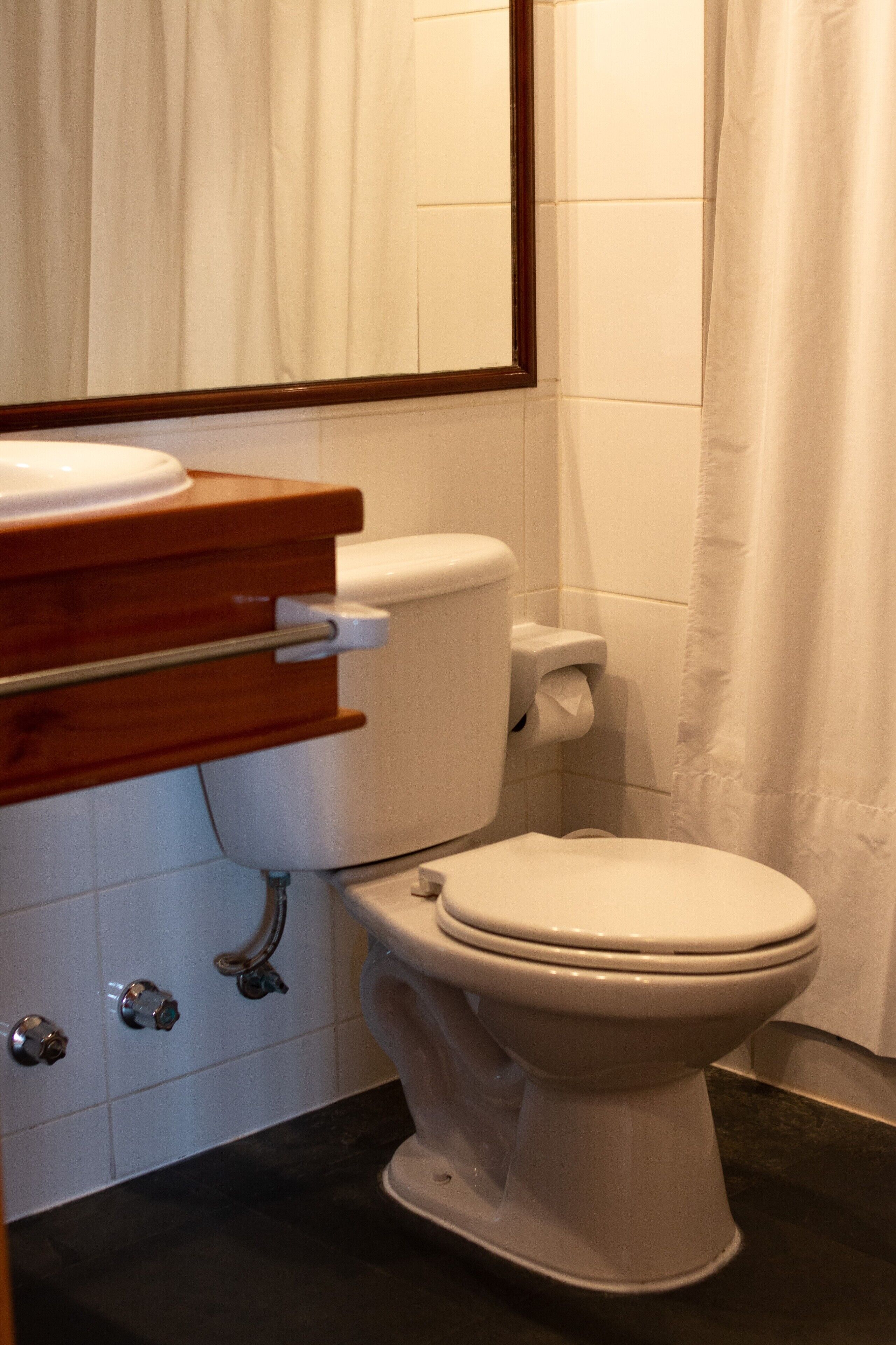 A bathroom with a white toilet, wooden vanity, and a black countertop.