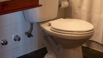 A bathroom with a white toilet, wooden vanity, and a black countertop.