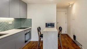 A compact kitchen with a herringbone tile backsplash, a microwave, and a marble countertop. - Bairro Alto Garden With A View by Homing (Lisbon)