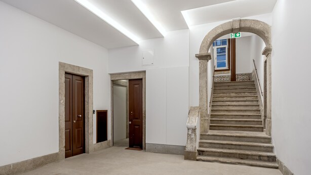 A hallway with a staircase, a wooden door, and a white wall. - Bairro Alto Garden With A View by Homing (Lisbon)