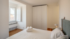 Un dormitorio con cama, armario, ventana y lámpara.