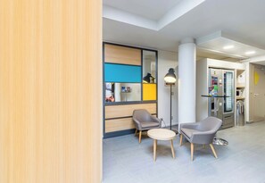 Un vestíbulo moderno con una recepción, dos sillones, una mesita y un separador de vidrio.