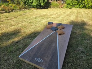 Un espace extérieur plat et rectangulaire, aménagé pour s’asseoir, orné d’un logo et entouré de gazon et de plantes.