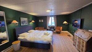 A hotel room with a bed, a chair, a dresser, a mirror, and a television.