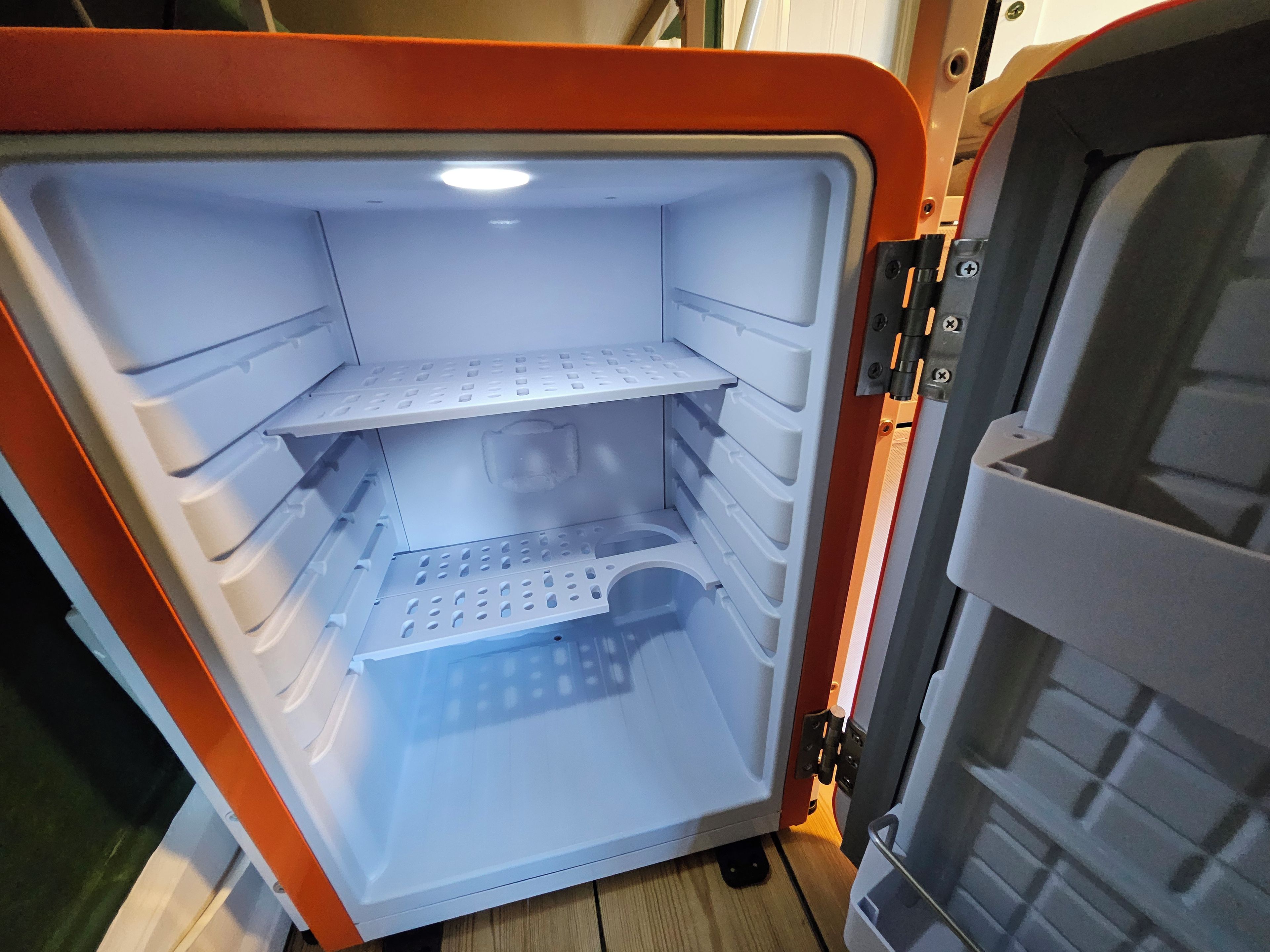 Un refrigerador vacío con varios estantes y un compartimento congelador.