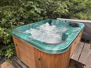 Un bain Ă remous avec jets dâeau, entourĂ© de verdure.