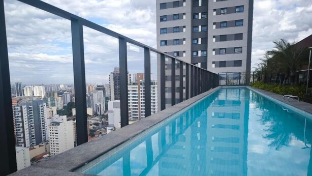 Una piscina al terrat amb vista a la ciutat, envoltada d'edificis alts.