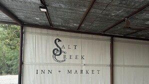 Eine große Metalldoppelgarage mit dem Schriftzug 'Salt Creek Inn + Market' und einem dekorativen 'S'.