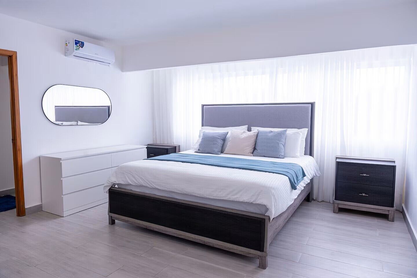 Een moderne slaapkamer met een bed, nachtkastjes, een spiegel en een airconditioning.