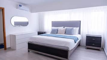 Een moderne slaapkamer met een bed, nachtkastjes, een spiegel en een airconditioning.