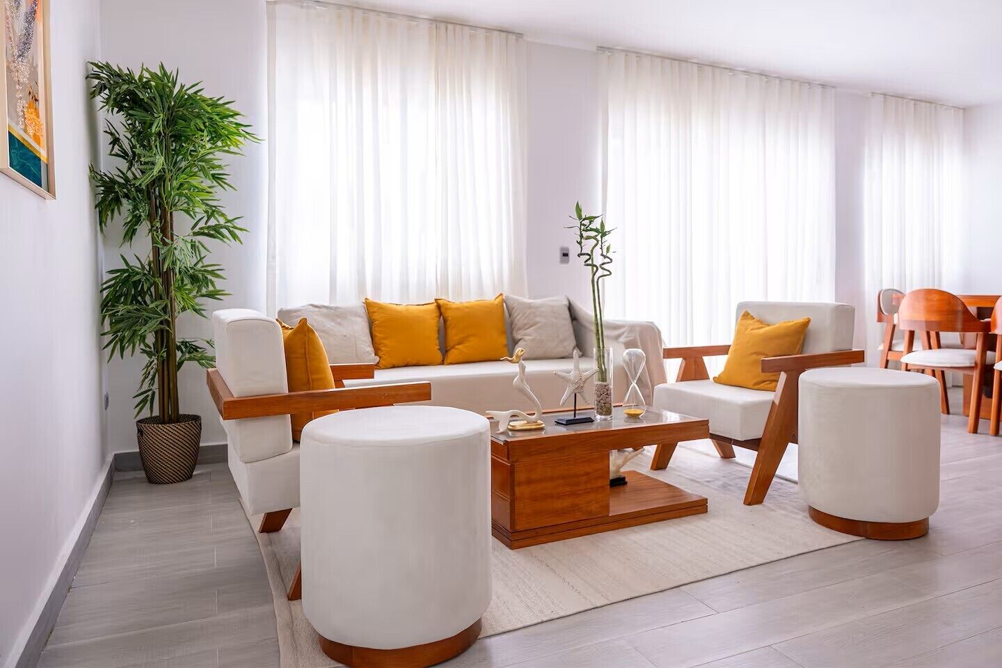 Een moderne woonkamer met een bank, twee fauteuils, een salontafel en een potplant.