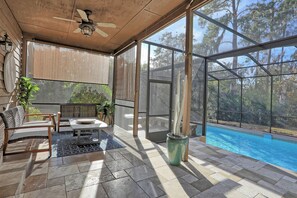 Ein überdachter Patio-Bereich mit Pool, Sitzgelegenheiten und Blick ins Grüne.