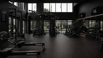 A gym with various exercise equipment, large windows, and a sign listing gym rules.