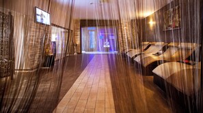 Un área de spa con una silla de masaje, una pantalla de televisión y una estatua.