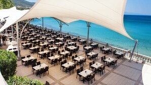 An outdoor dining area with tables and chairs, overlooking a body of water.